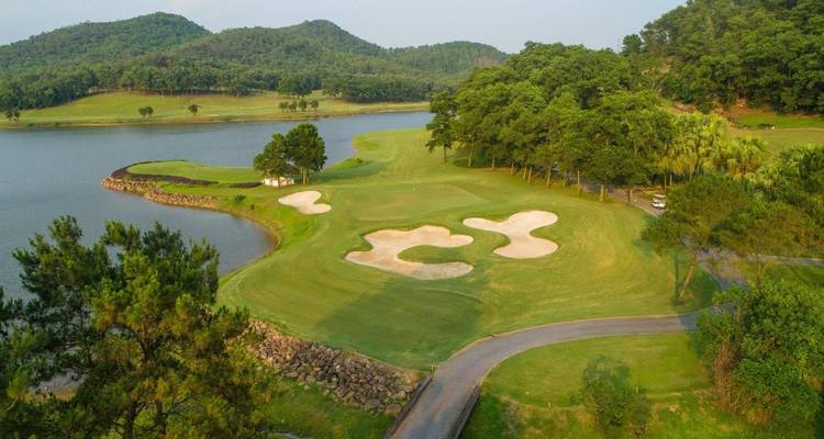 Prachtige golfbaan aan een meer met dichte begroeiing.