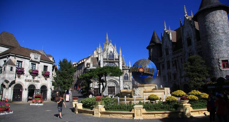Des personnes se promenant dans un parc à thème avec des bâtiments ressemblant à des châteaux.