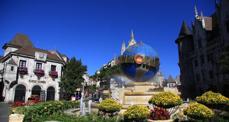 Fontaine avec grand globe et parterres de fleurs colorés.