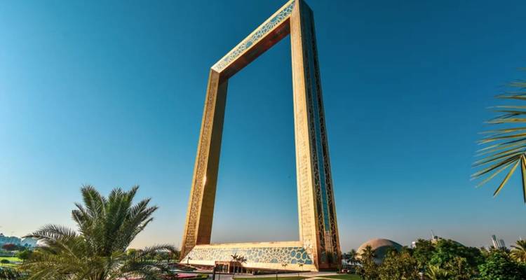 Der aufragende Dubai Frame vor einem klaren blauen Himmel, umrahmt von Palmen.
