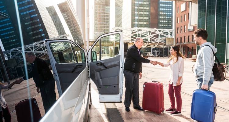Menschen steigen mit Koffern in ein Fahrzeug ein