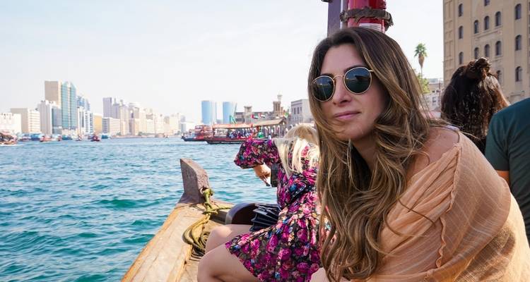 Frau sitzt auf einem Boot mit einer Stadtsilhouette im Hintergrund