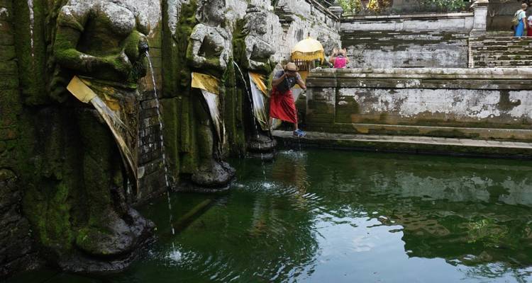 Bassin sacré avec des statues et une personne pratiquant des rituels.