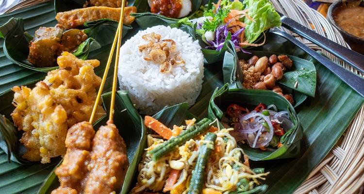 Repas traditionnel indonésien avec du riz et divers plats d'accompagnement servis sur des feuilles de bananier.