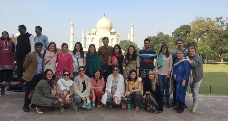 Le groupe de touristes pose sur une plateforme avec le Taj Mahal bien en évidence derrière eux