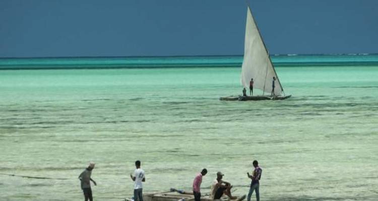 Menschen bij een zeilboot aan de waterkant.