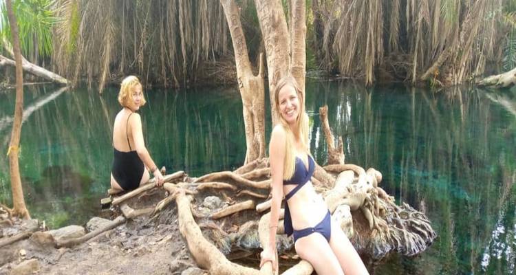 Twee vrouwen zittend bij een natuurlijke bron met helder water.
