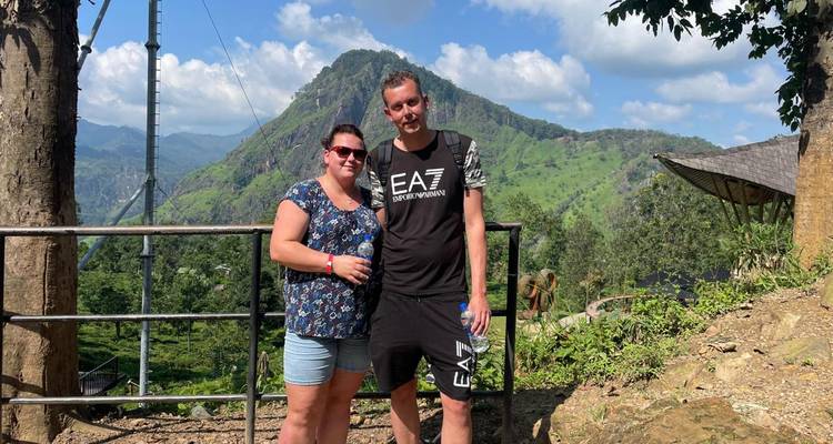 Couple posant avec un arrière-plan de montagne verdoyante luxuriante.
