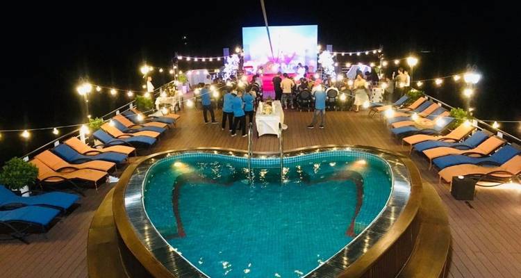 Luxueuze buitendiner setting met zwembad op een cruisedek 's nachts.