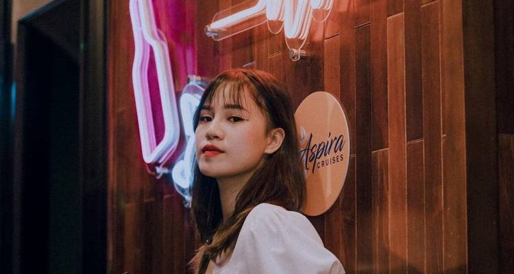 Persoon die poseert naast neonlichten en een cruisebord.