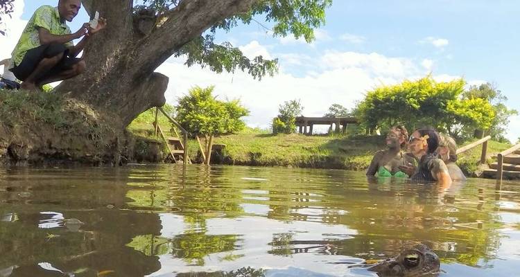 People in a river with a hippopotamus lurking nearby.