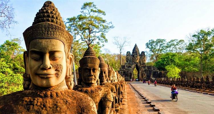 Rangée de statues menant à une porte avec une route.