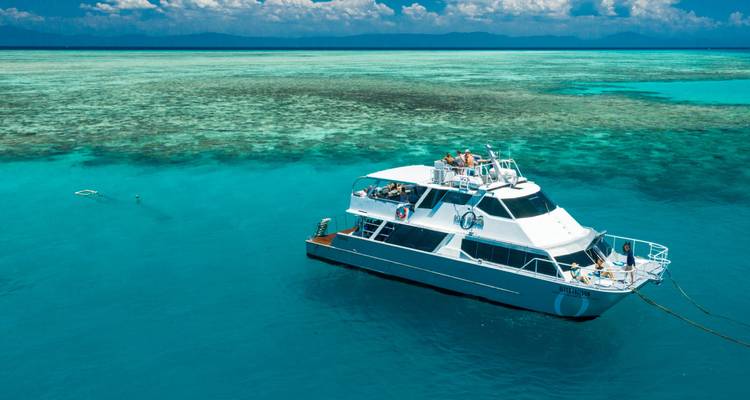 A large boat anchored in clear blue waters with visible coral reefs.