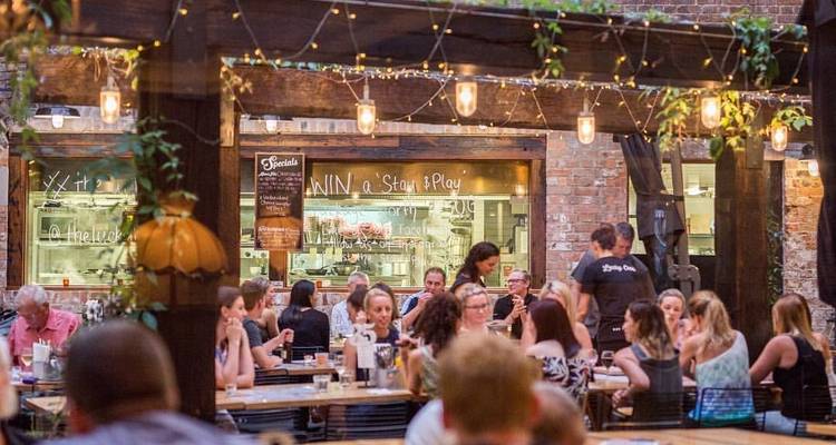 Scène de repas en plein air avec des gens qui socialisent sous les lumières.