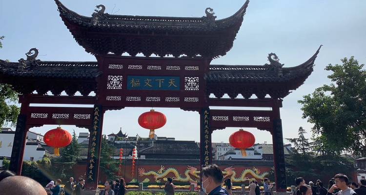 Traditional gate with red lanterns and people in foreground.