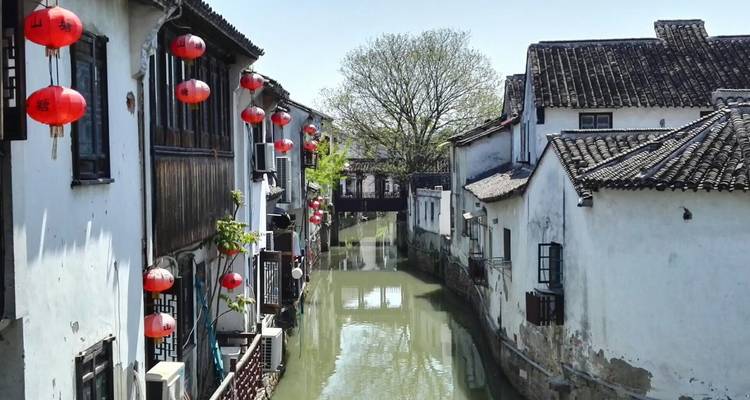 Narrow canal lined with traditional Chinese houses and red lanterns.