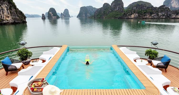 Pool with a swimmer on a cruise ship with scenic limestone islands.