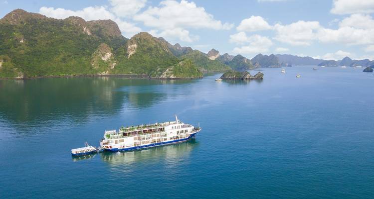 A cruise ship sailing through the waters with limestone islands in view.
