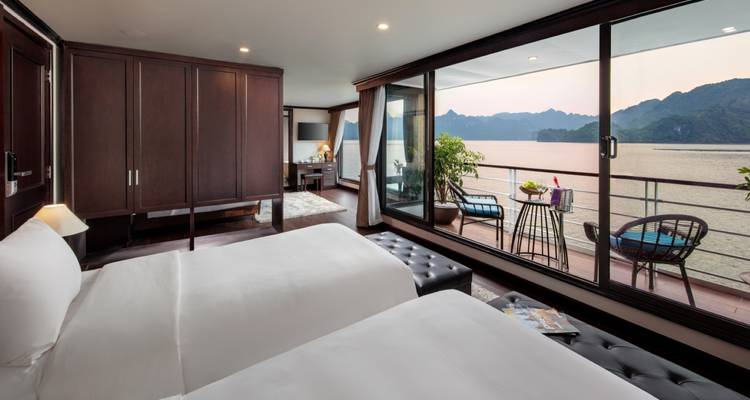 Spacious cruise suite with wide windows offering views of the sea and mountains.