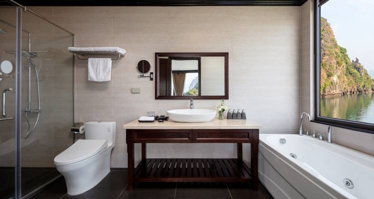 Elegant cruise suite with a bathtub and views of the ocean from large windows.