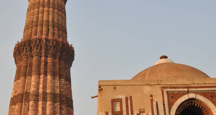 Een historische hoge toren naast een koepelvormige structuur.