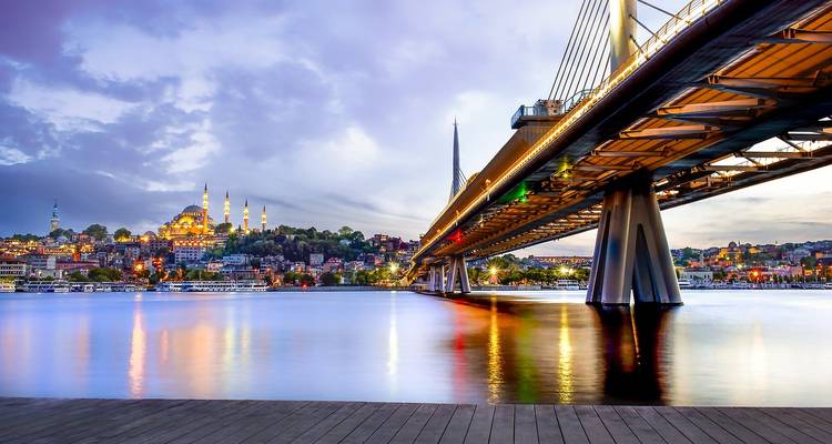 Stadsgezicht met een brug over een rivier en een prominente moskee in de verte.