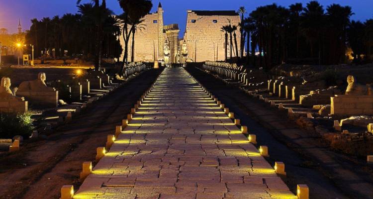 Luxor Tempel verlicht in de nacht met een pad omzoomd door beelden