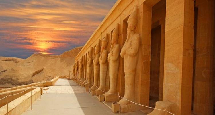 Estatuas en el Templo de Hatshepsut contra un cielo vibrante.