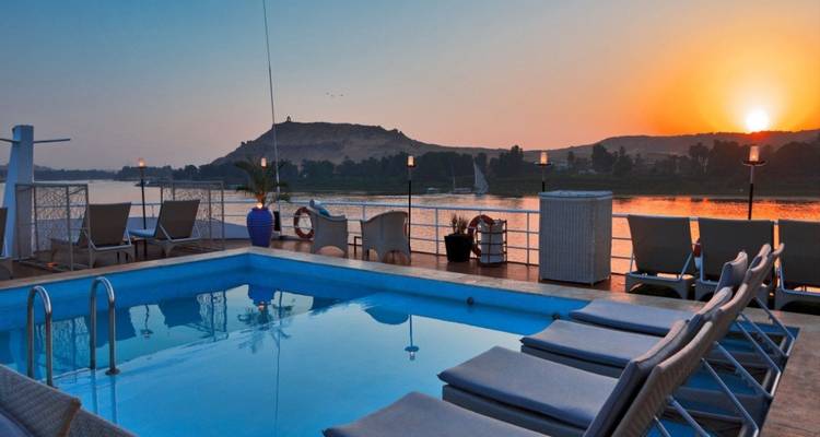 Pool auf einem Kreuzfahrtschiff-Deck mit Blick auf den Fluss bei Sonnenuntergang.