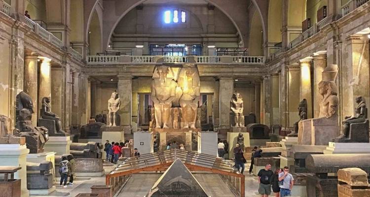 Innenraum eines ägyptischen Museums mit großen Statuen und Besuchern.