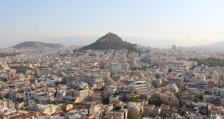 Vista panorámica del paisaje urbano de Atenas con una colina en la distancia.