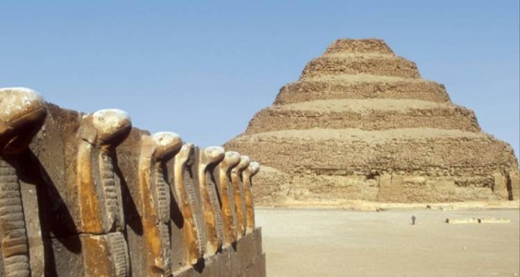 Stenen piramide met een rij slangenbeelden.