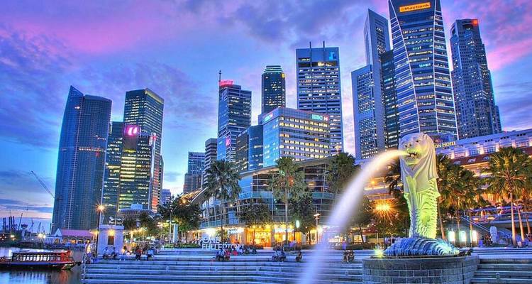 Merlion-Brunnen mit der lebendigen Abendskyline des Singapurer CBD unter farbenfrohen Wolken.