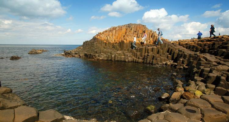 Visitors exploring the Giant's Causeway rock formations by the sea.