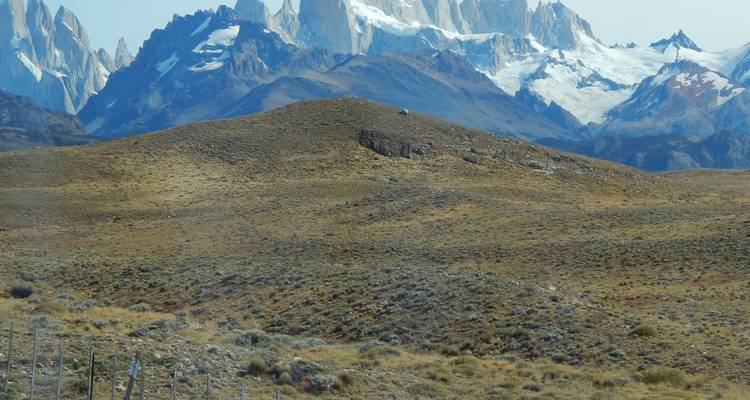 Bergige Landschaft mit fernen schneebedeckten Gipfeln und zerklüftetem Gelände.
