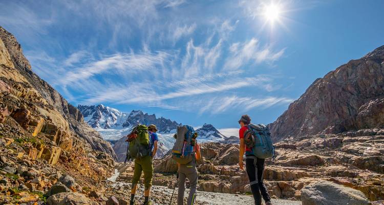 Wanderer, die entlang eines felsigen Bergpfads mit majestätischen Gipfeln im Hintergrund gehen.