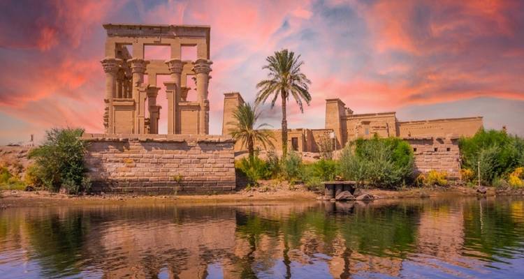 Philae-tempel met roze zonsonderganglucht weerspiegeld in het water.