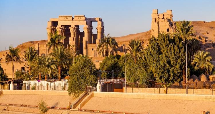 Tempel omgeven door weelderig groen langs een rivieroever.