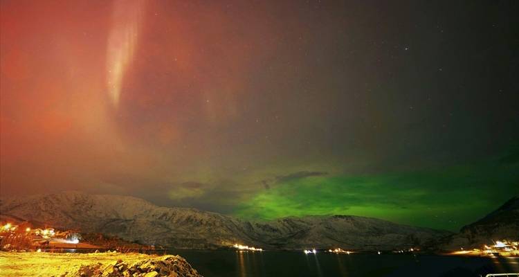 Aurora boreal sobre montañas nevadas.