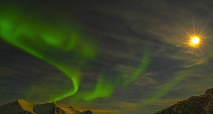 Aurora boreal brillante sobre picos montañosos.