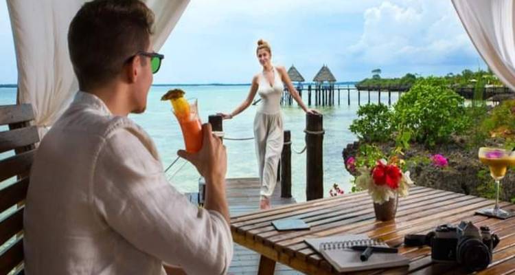 Ein Paar in einem Strandresort, Mann mit einem Getränk und Frau beim Posieren.