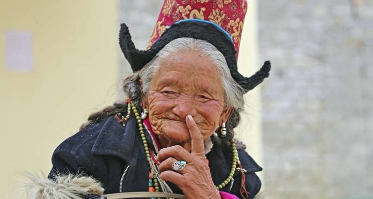 Elderly woman in traditional attire smiling.