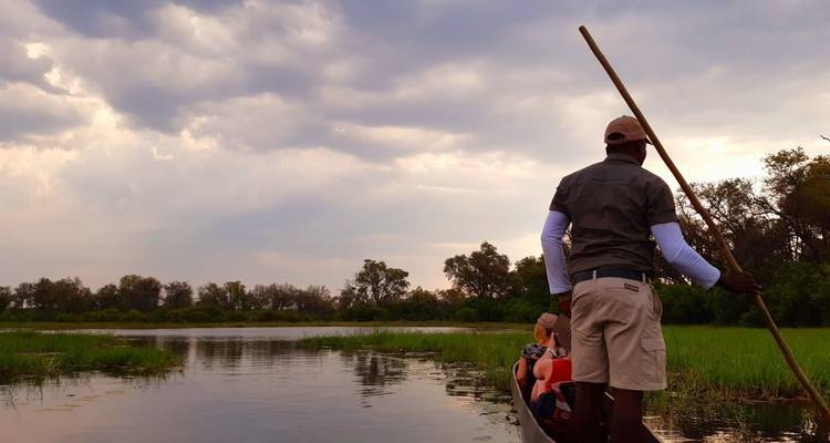 Person on a canoe in a river with a pole guide.
