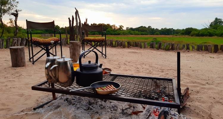 Outdoor cooking scene with a grill and two kettles.