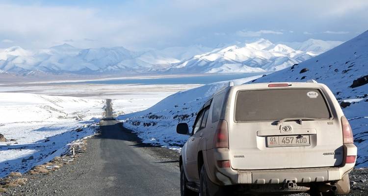 Snowy mountain road with a vehicle.