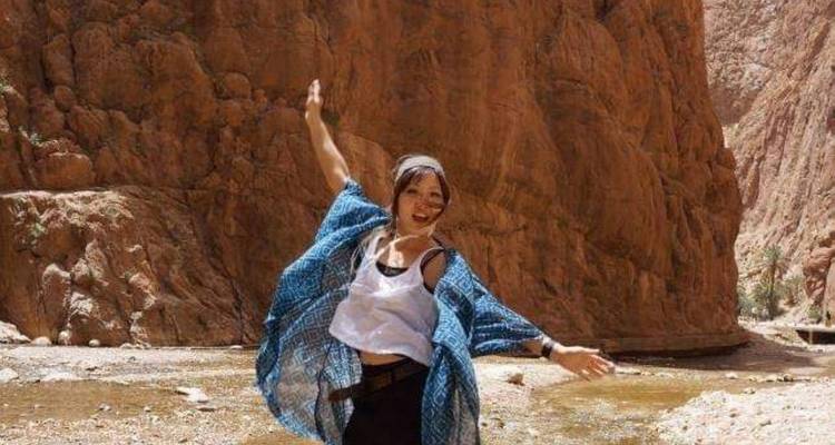 Una mujer feliz bailando en un cañón rocoso.