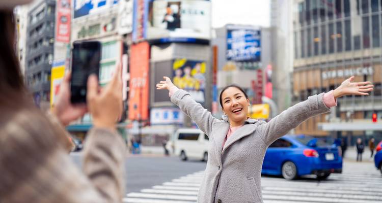 Tourist posing joyfully in a bustling city area.