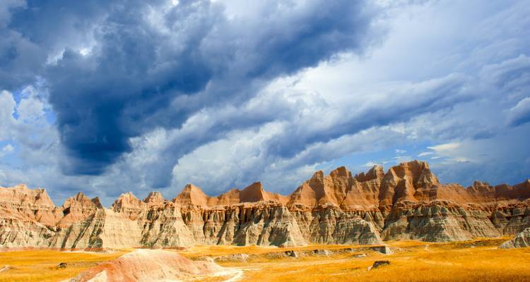 Dramatic rock formations and stormy sky over a desert landscape.