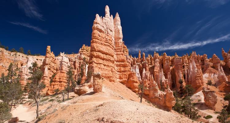 Tall, orange rock formations against a deep blue sky in a desert setting.