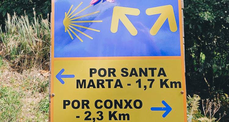 Señal amarilla del Camino de Santiago que indica las distancias a Santa Marta y Conxo.